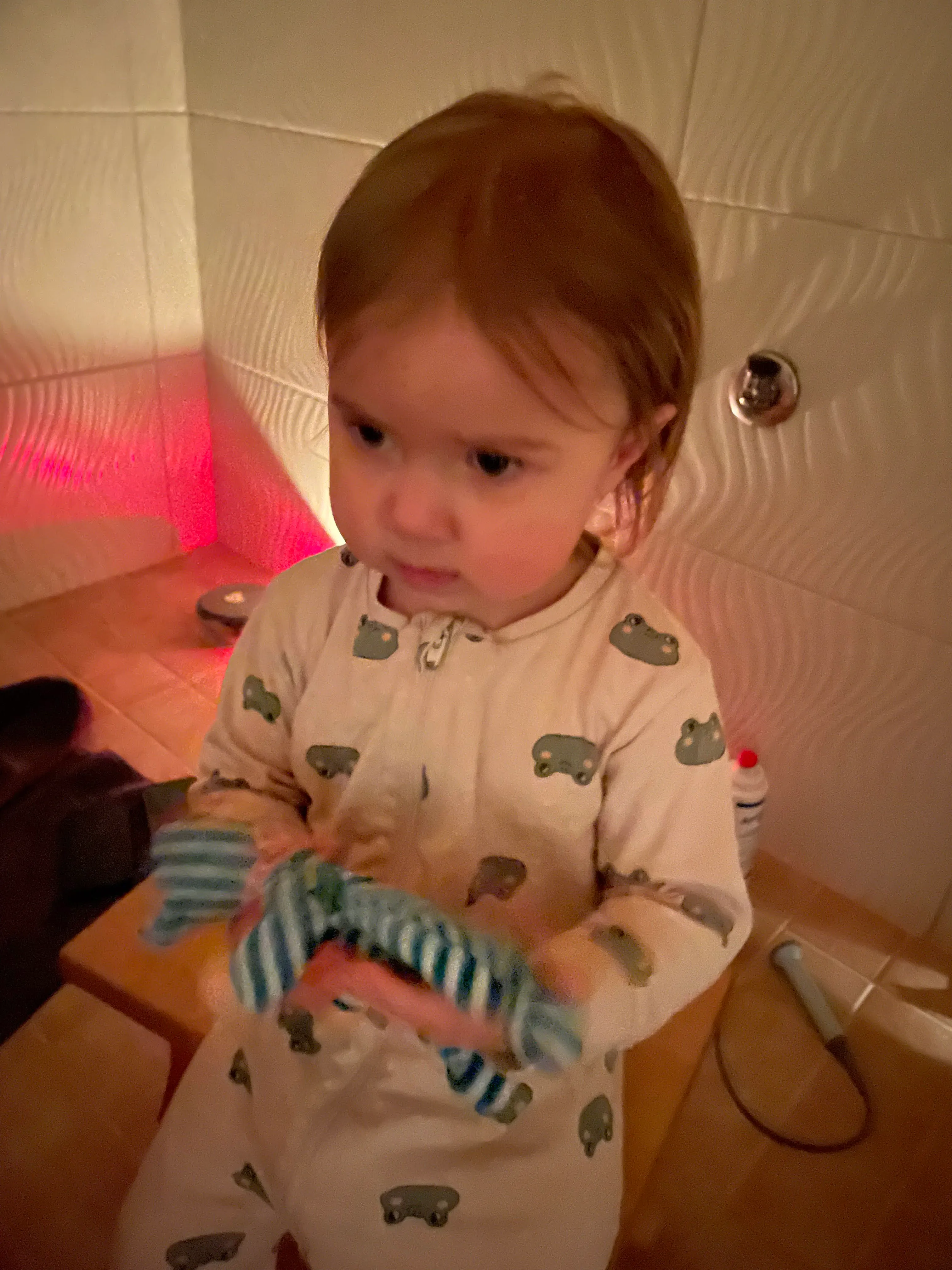 Sara's daughter standing beside the bathtub in frog pajamas after her baby brother was born