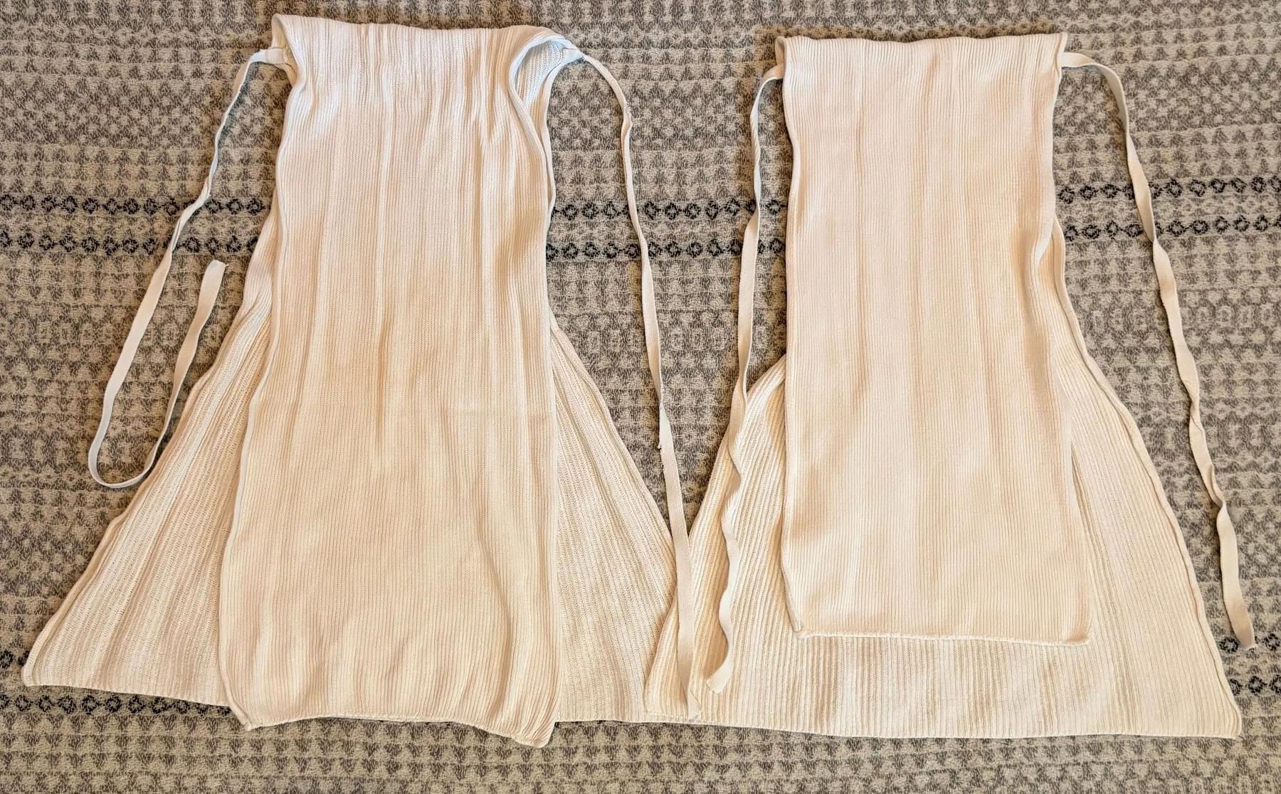 Disana and Popolini cotton tie nappies side by side, with their narrow panels folded over the wider sections to compare their shape and length