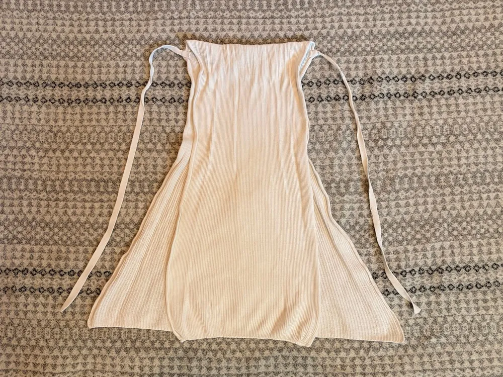 Step 1: The cotton nappy laid flat with its narrow panel folded over the wider section and the ties at the top.