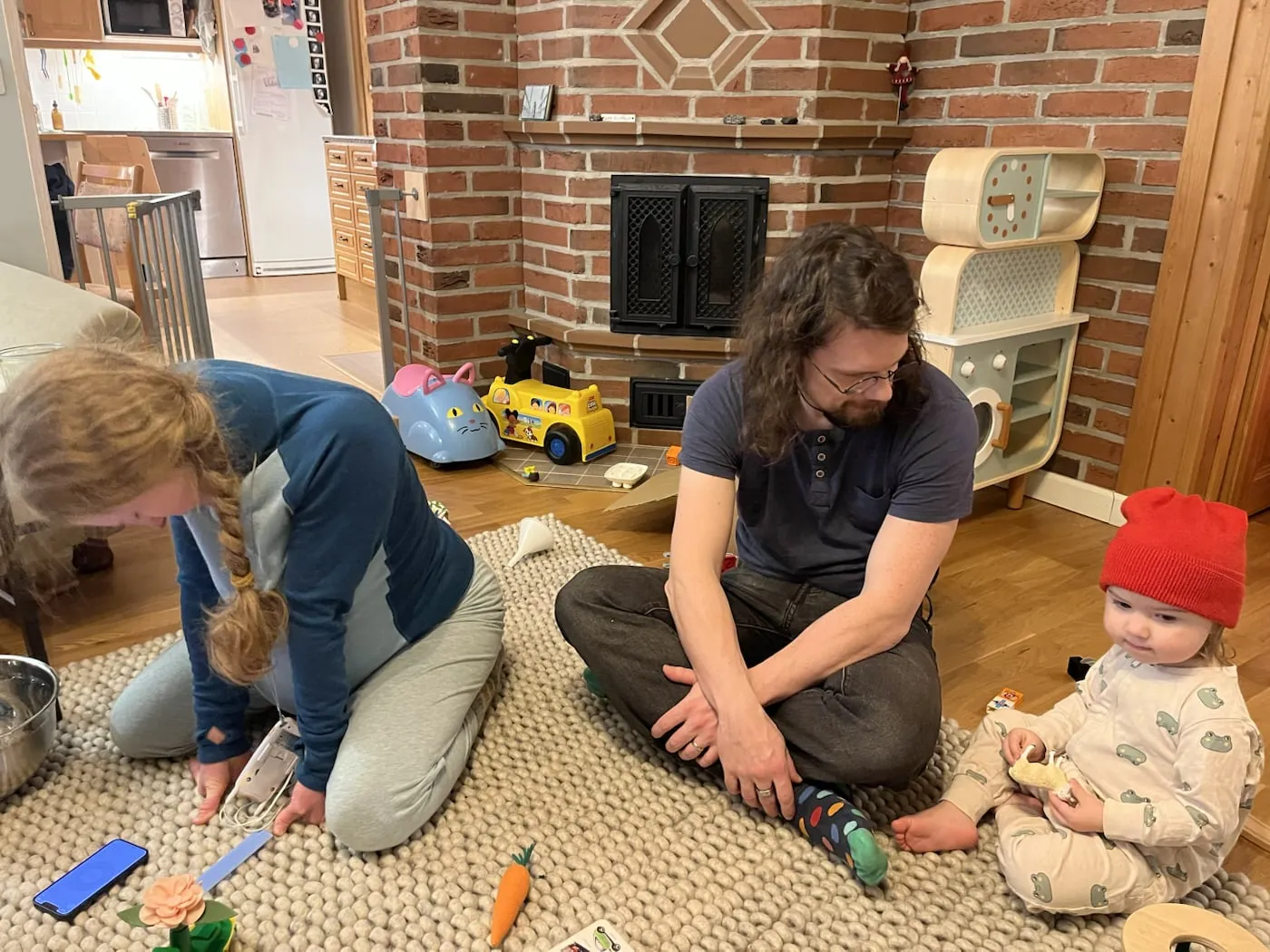 Sara kneeling on the rug during labor, with her husband and young daughter beside her at home